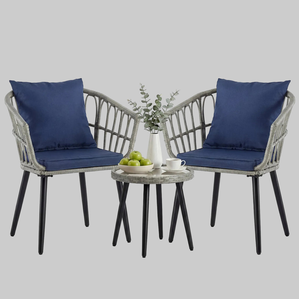 A grey 3-piece PE rattan outdoor bistro set with two padded chairs and a tempered glass-top table on a cozy apartment balcony.