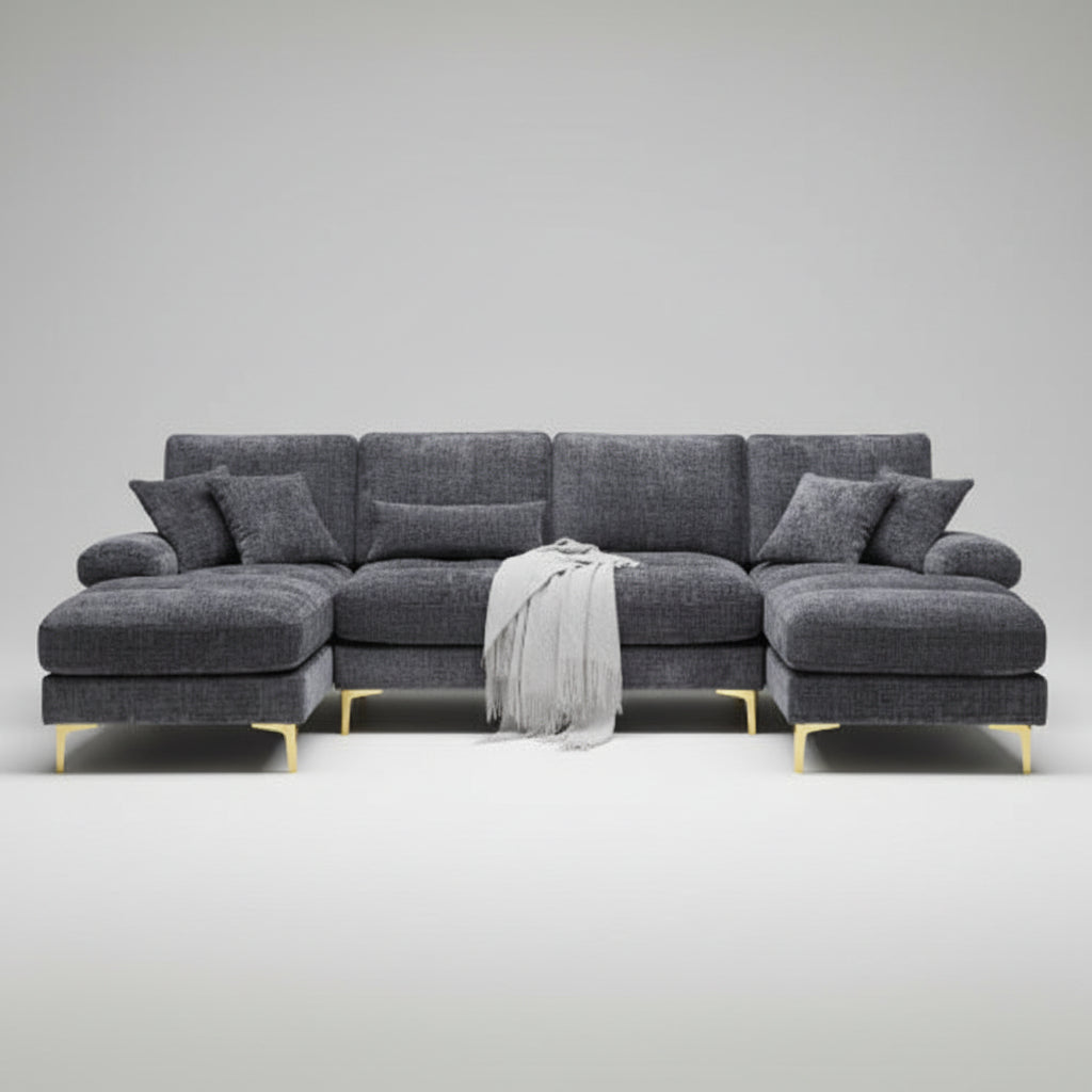 Gray sectional sofa in a living room with a rug and bookshelf.